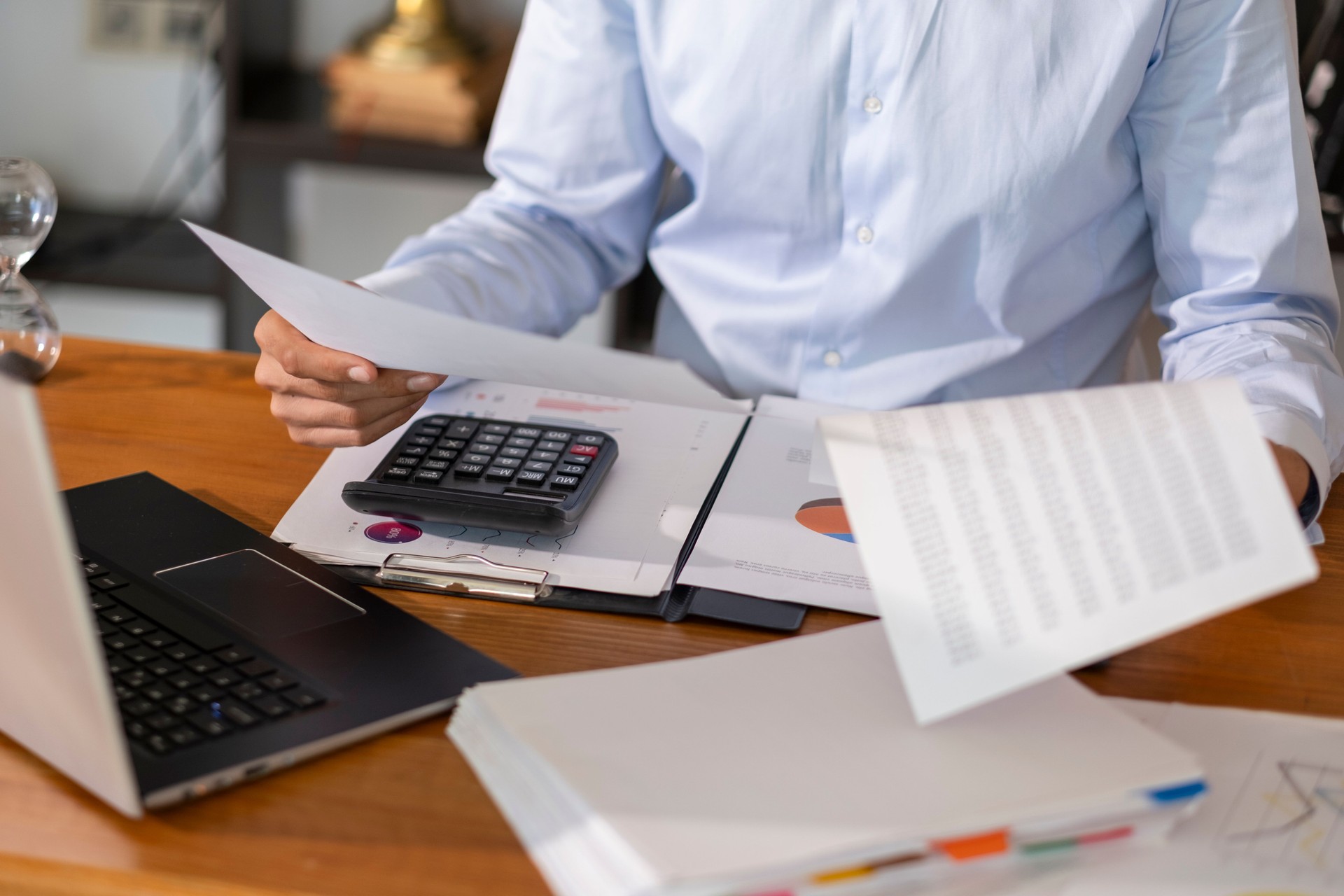 Businesswoman examining financial reports and using calculator, performing accounting tasks in office workplace